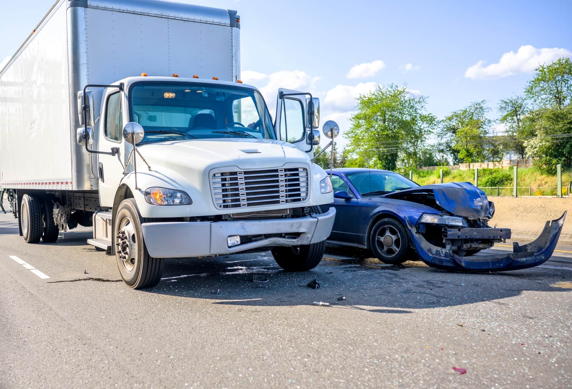 A large white semi-truck and a black sedan with severe front-end damage are involved in a collision on a clear day. Debris litters the road, highlighting the importance of Commercial Auto Insurance for protection against accidents like this.