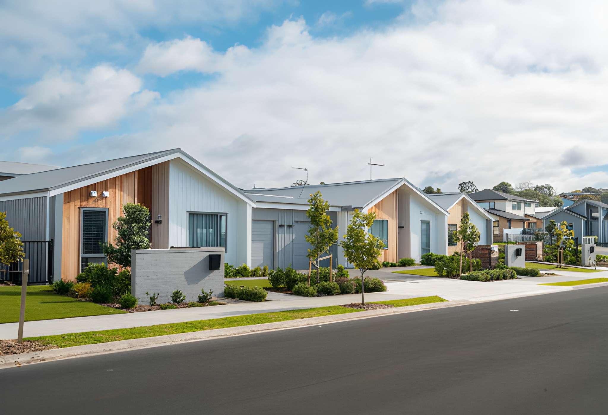 A row of modern single-story houses with well-maintained lawns and young trees lines a clean suburban street under a partly cloudy sky—ideal for those seeking condo and townhome insurance in Algonquin, IL.