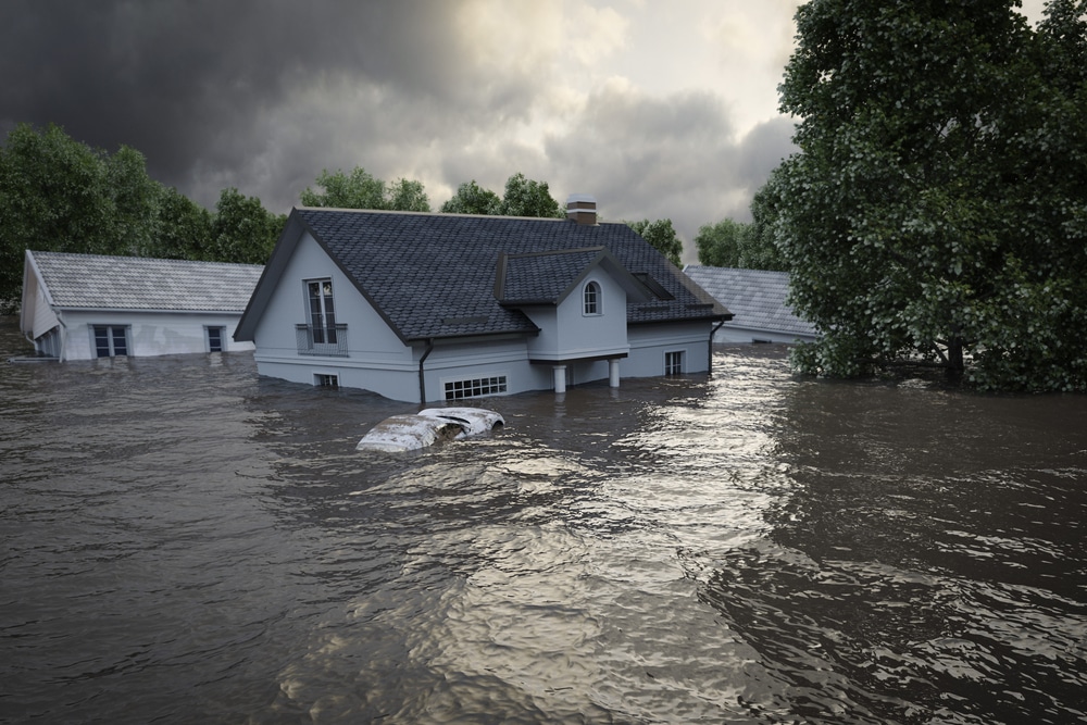 A house is partially submerged in floodwater, with only the upper floor and roof visible. A car is mostly underwater in front of the house. Homeowners insurance Antioch can help protect against such unexpected disasters.