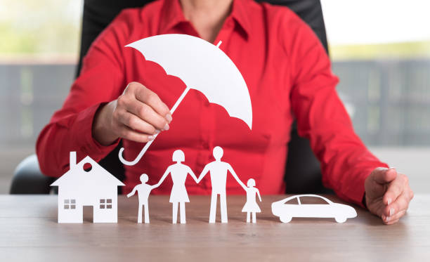 A person in a red shirt holds a paper umbrella over paper cutouts of a house, a family of four, and a car, symbolizing protection or homeowners insurance coverage in Alsip IL.