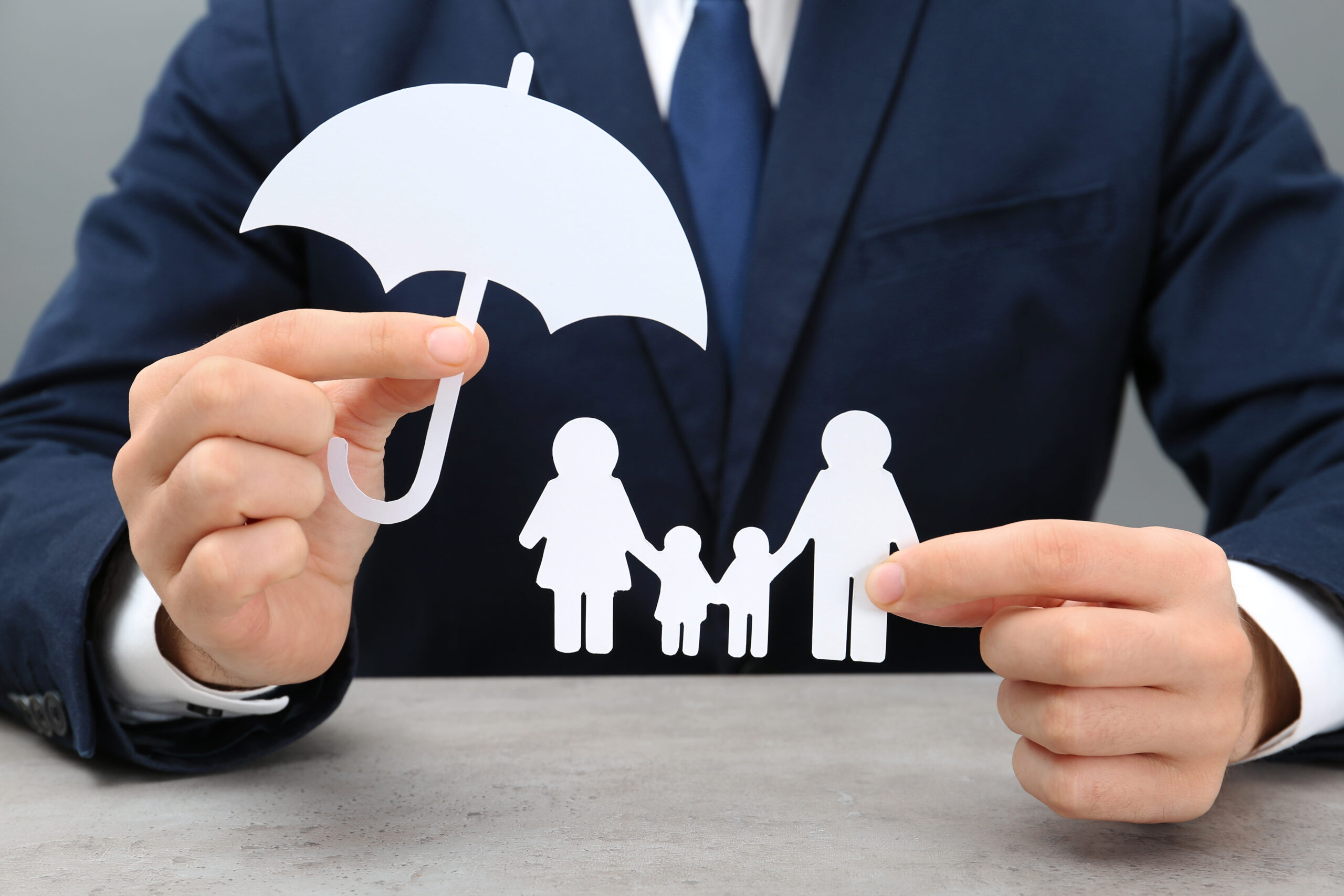 A person in a suit holds paper cutouts of a family and an umbrella, symbolizing family protection or insurance—perfectly capturing the essence of homeowners insurance Berwyn.