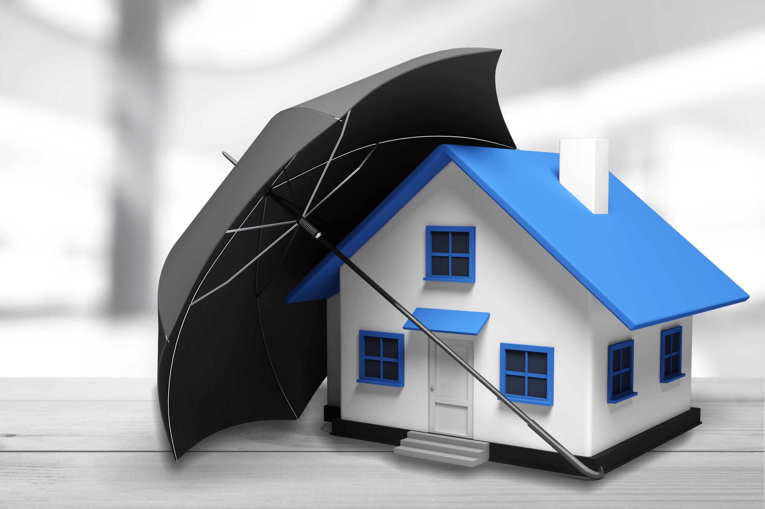 A small model house with a blue roof and blue window frames sits on a table, partially covered by a large black umbrella, symbolizing the protection offered by homeowners insurance Berwyn.