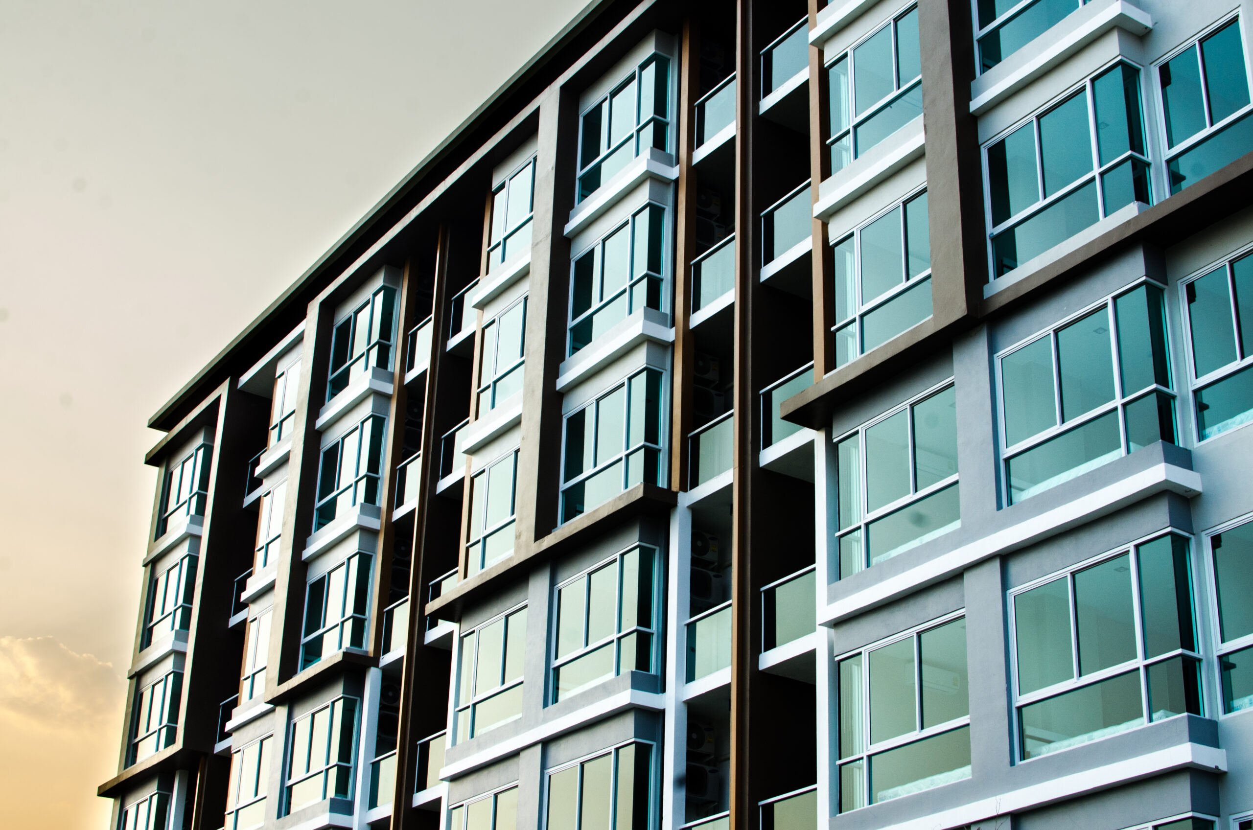 A modern multi-story apartment building with large glass windows and balconies, featuring a gray and white exterior under a partly cloudy sky—ideal for those seeking Homeowners Insurance in Blue Island.