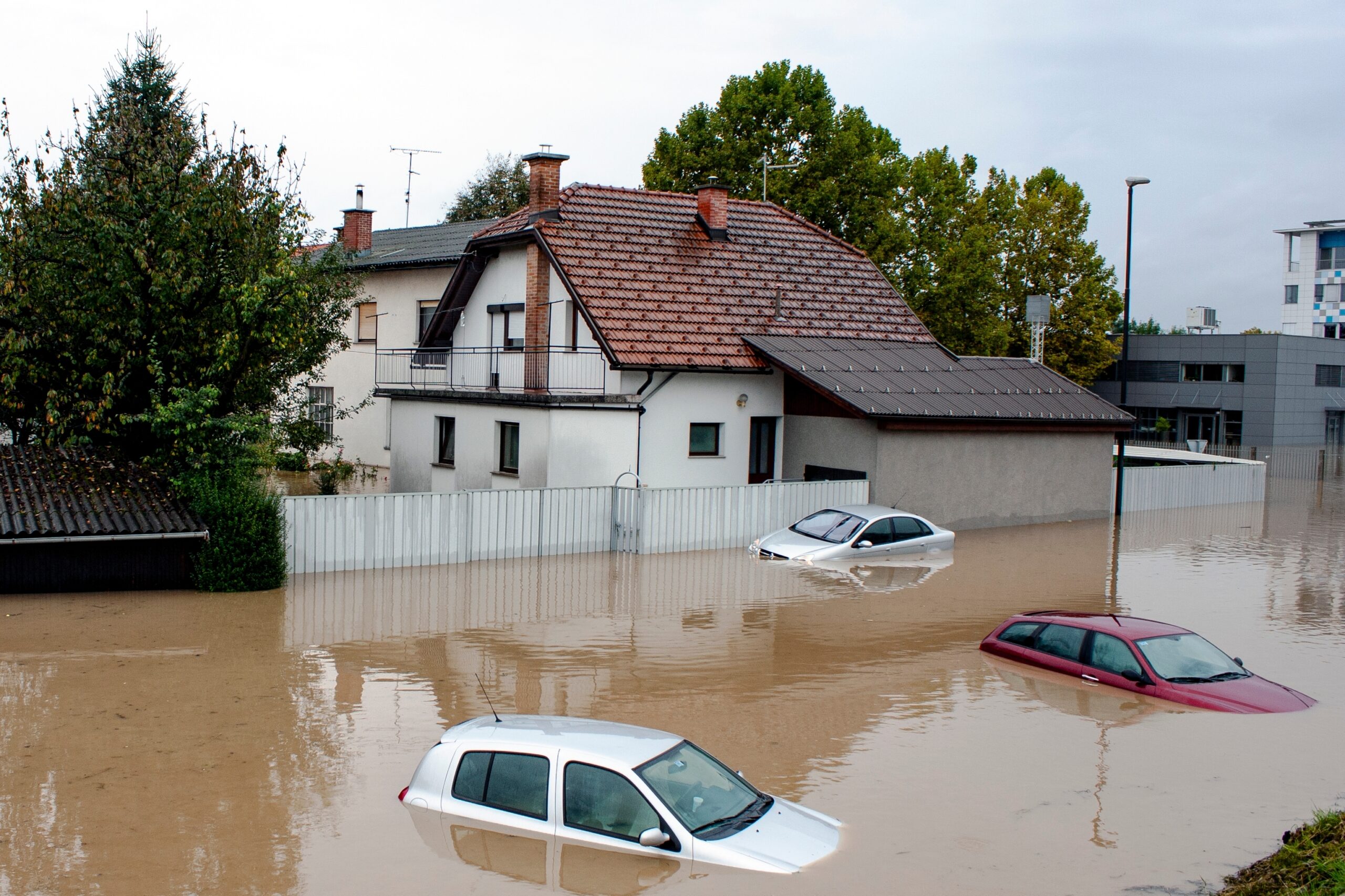 Several cars and houses are partially submerged in floodwaters on a residential street in Brookfield, IL, with muddy water covering much of the area—highlighting the importance of homeowners insurance for local residents.